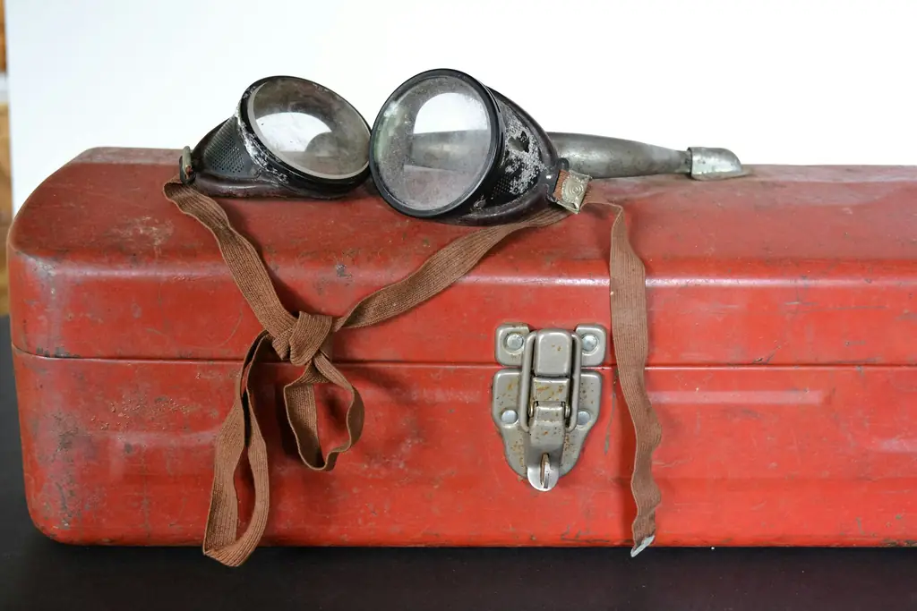 Worn red metal toolbox with safety goggles on top